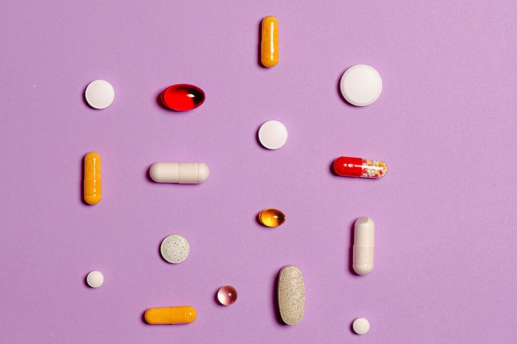Various pills and capsules on a purple background