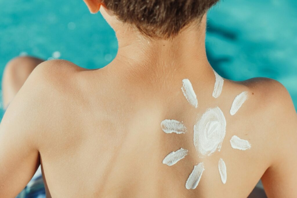 Sunscreen on child's back in shape of sun