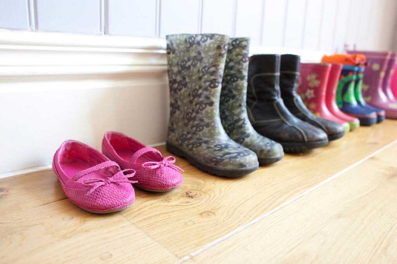 Children's and adult's shoes lined up in a hall.