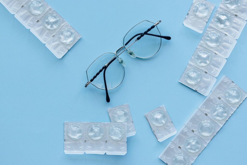 eye glasses and contact lenses placed on a blue surface