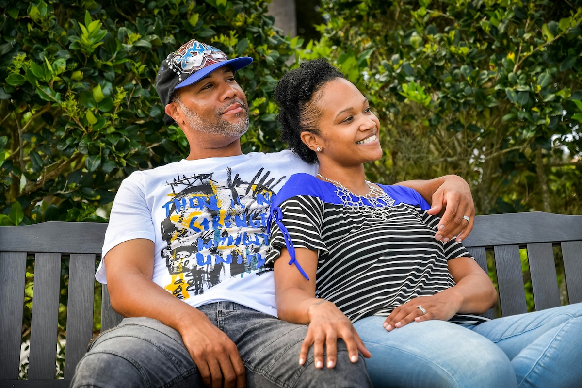 a happy couple sitting on a bench in a park