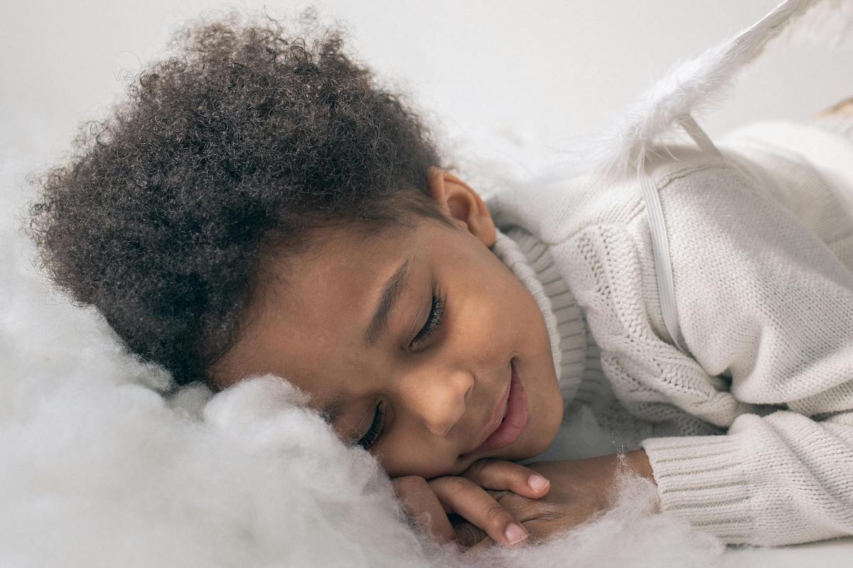 Child naps with a smile on a cloud made of cotton.