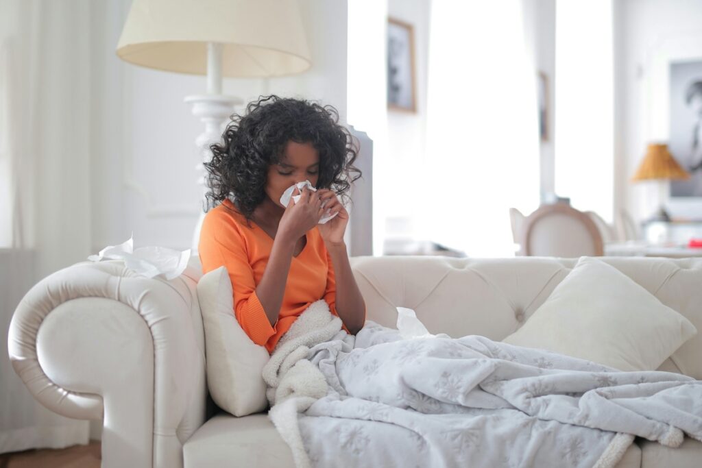 kid sitting on couch cleaning nose with tissue