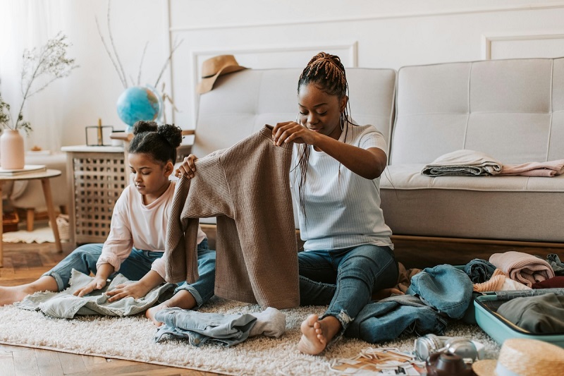 a baby and a parent sitting on a floor and doing home chores