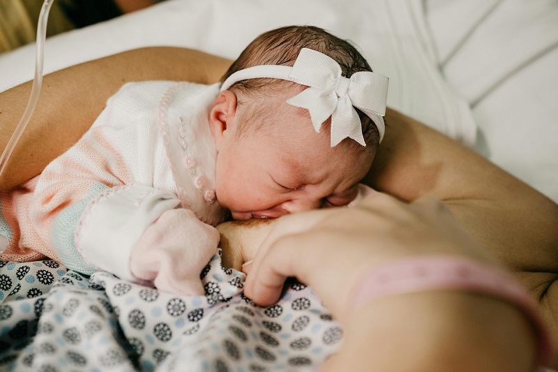 toddler with white head band breastfeeding