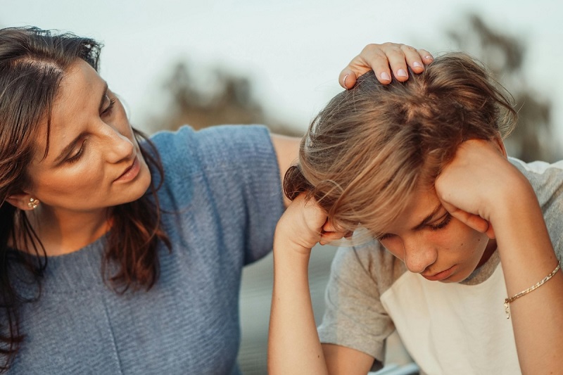 A parent talking and condoling a big child while placing hand on the head