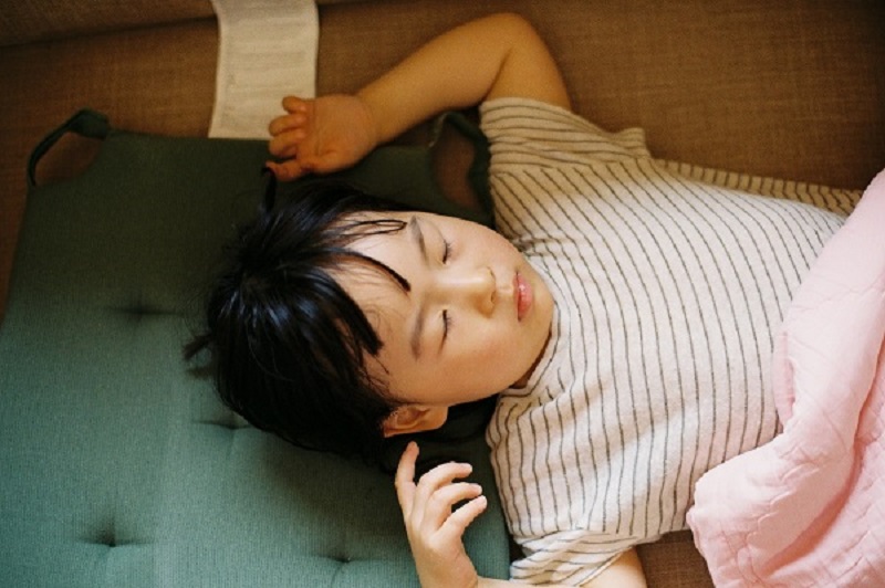 baby with pink lining shirt sleeping on a bed