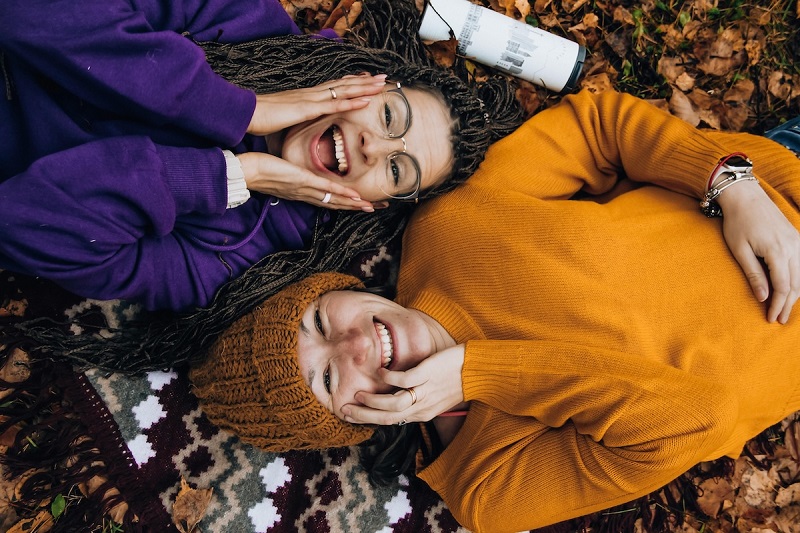 Two adults lying in opposite direction holding hands on the face