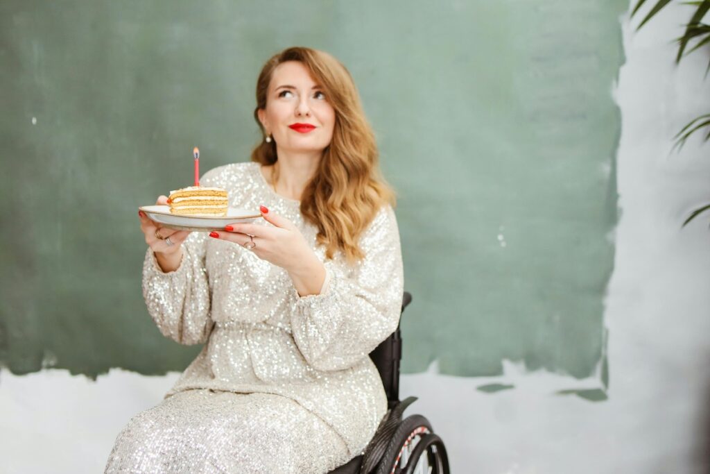 Person in a wheelchair celebrating a birthday while holding a cake