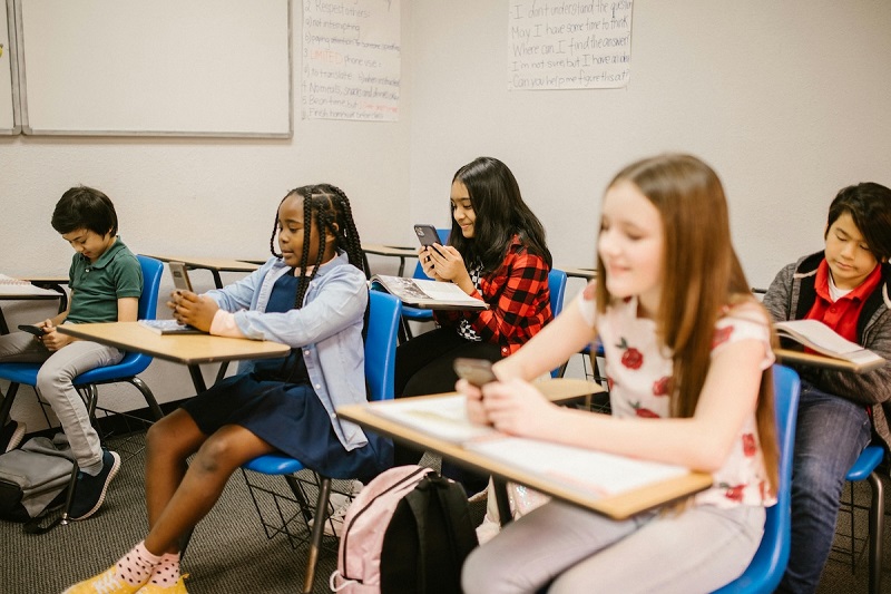 kids sitting in a class room and using mobile