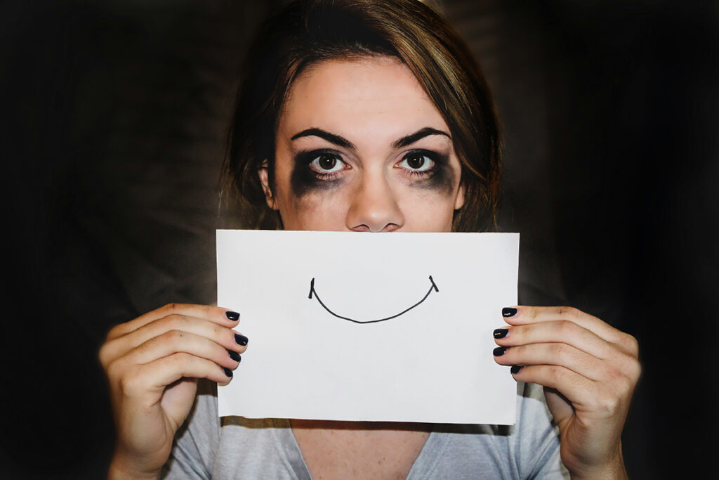 A person standing and holding a white paper with a smiley