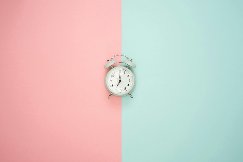 a small clock with a pink and green background