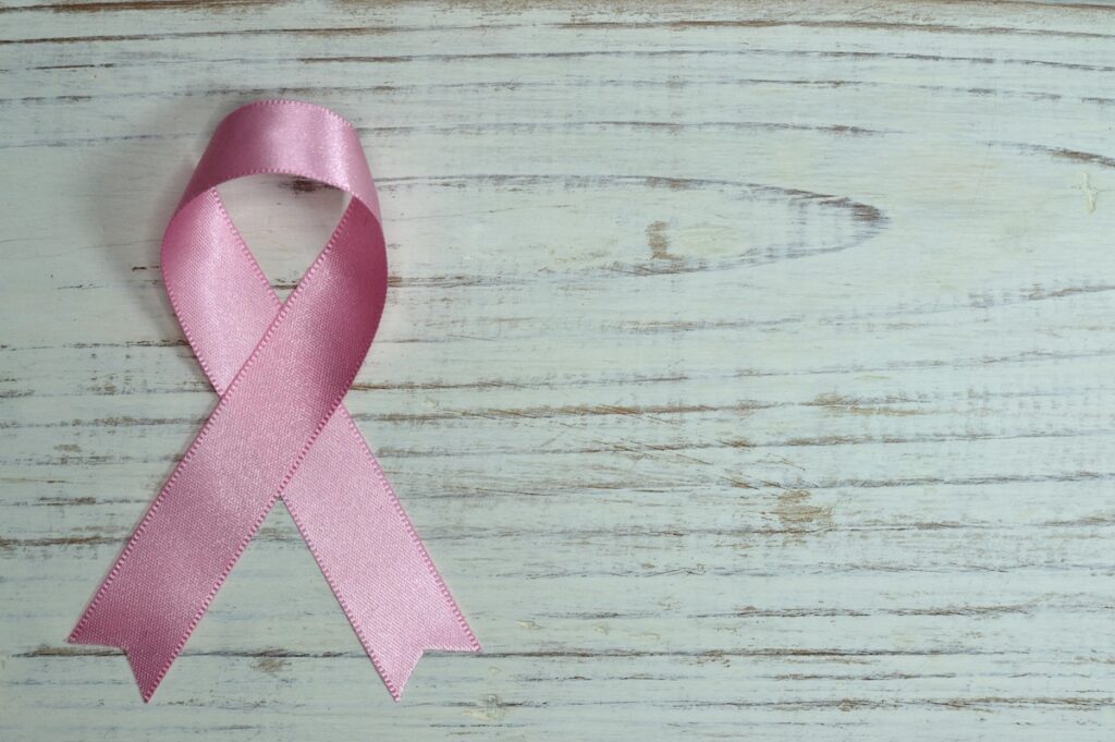 Pink ribbon on white wooden background