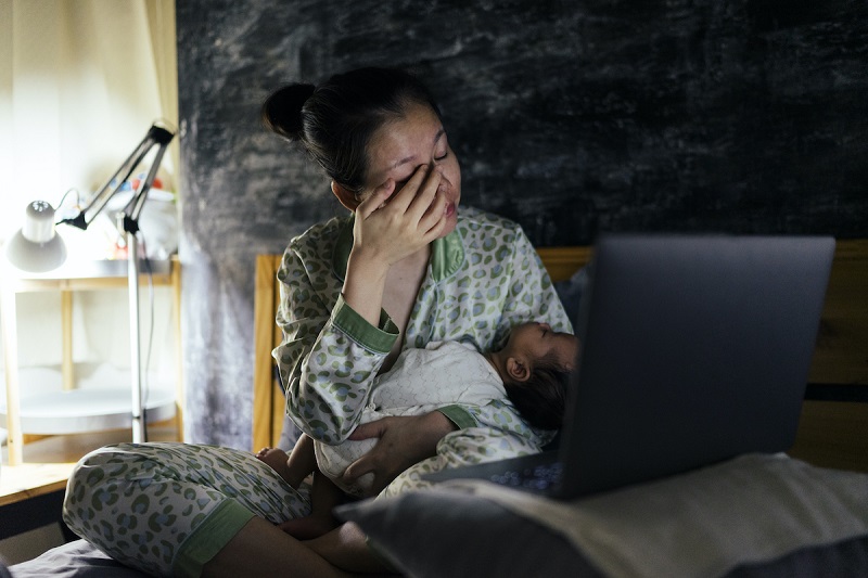 a parent holding a child and sitting on a bed late night