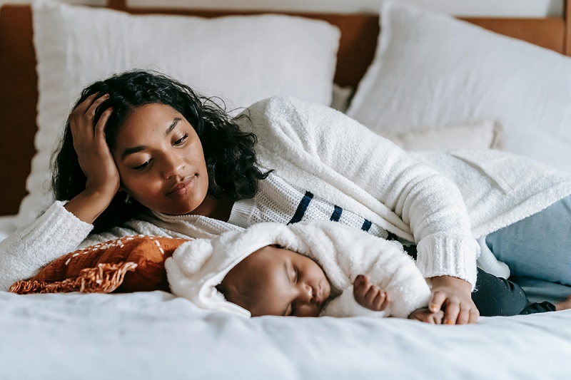 a parent and a child laying sidewise on a bed