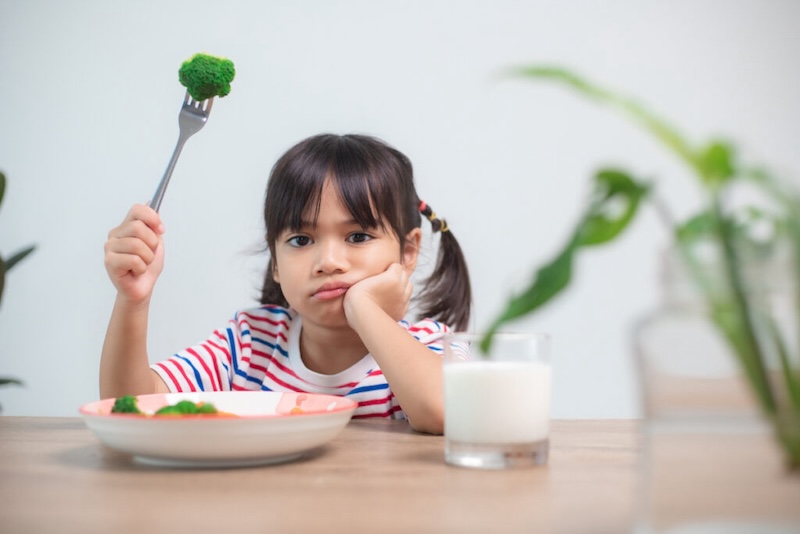 Nutrition & healthy eating habits for kids concept. Children do not like to eat vegetables. Little cute girl refuses to eat healthy vegetables.