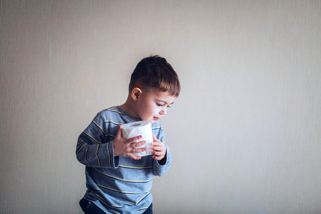 kid standing and holding a tissue paper roll