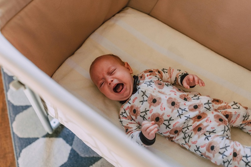 baby lying in baby bed and crying