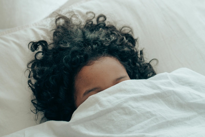 kid sleeping with half face covered with blanket