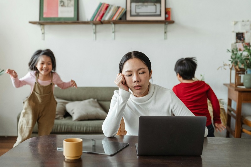 parent working on laptop while kids playing in the background