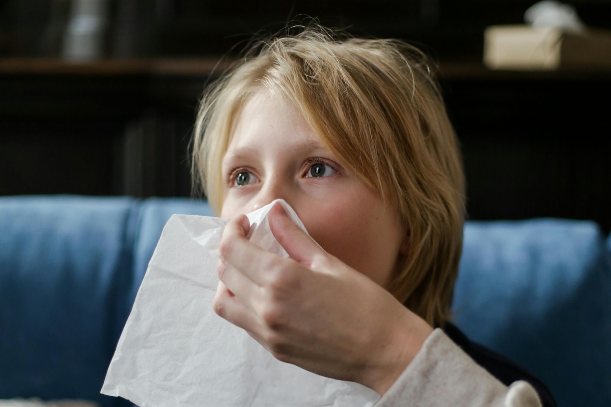 a child cleaning the nose using tissue paper