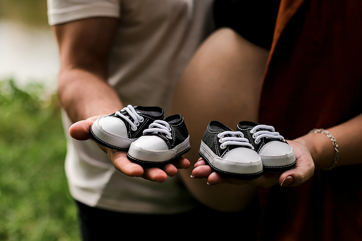 a pregnant couple holding baby shoes