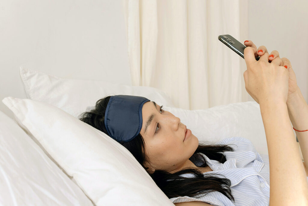 a person lying on bed and using mobile phone