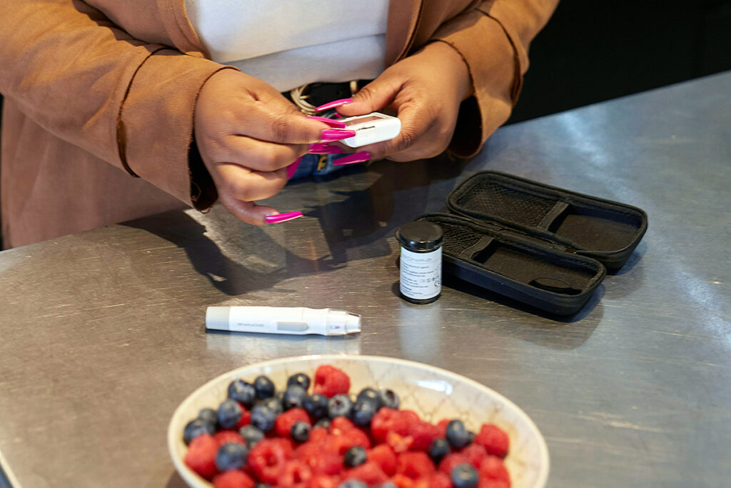 an adult checking blood sugar level while cherries are present in font