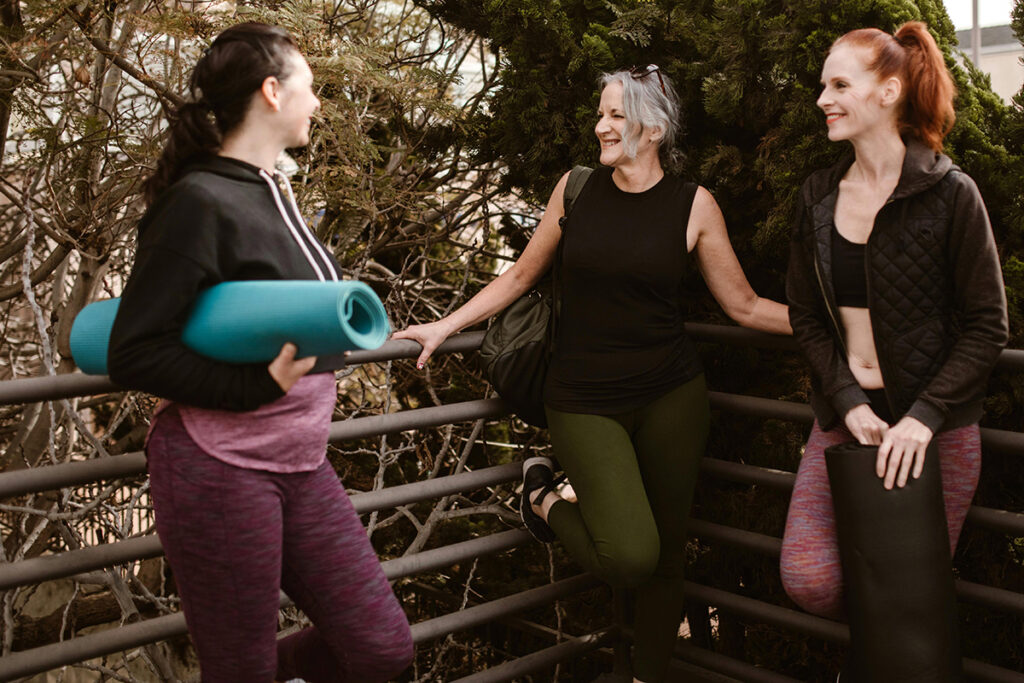 three ladies in exercise dress and holding yoga mats