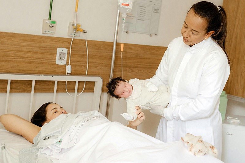 nurse handing over a newly born child to the parent