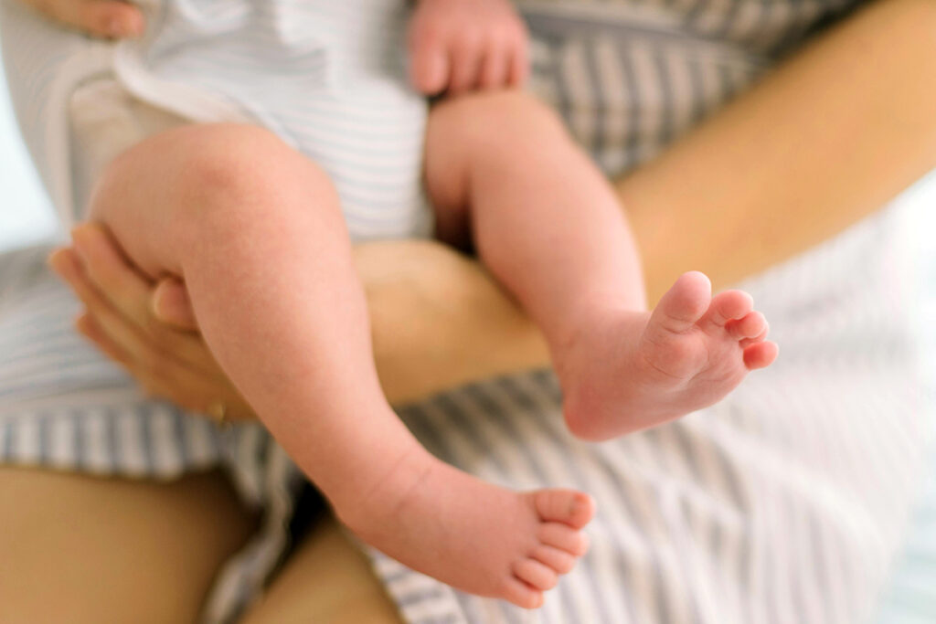 zoomed baby legs while holding by an adult