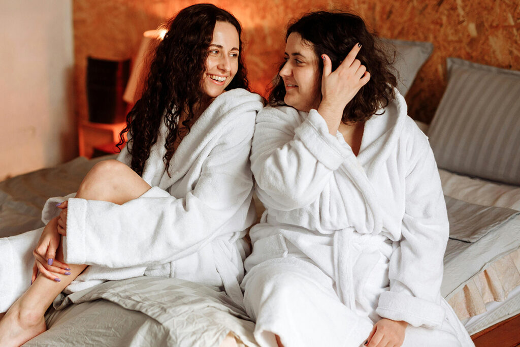 two adults sitting on a bed earing bathing suits