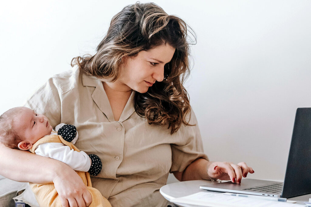 parent working while holding baby