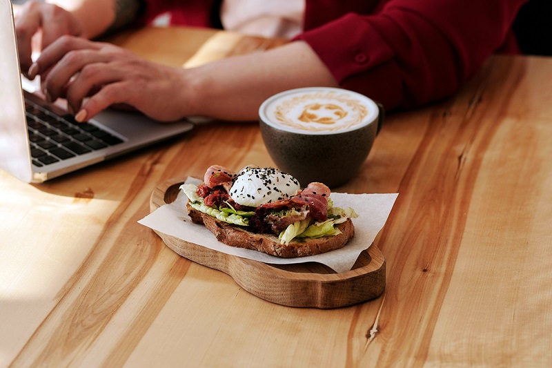 coffee and protein rich food on the table while the person is using the laptop