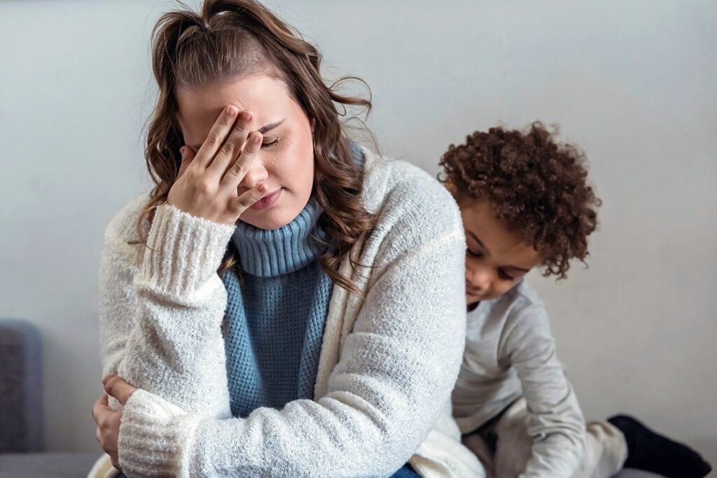 Stressed parent with child behind them