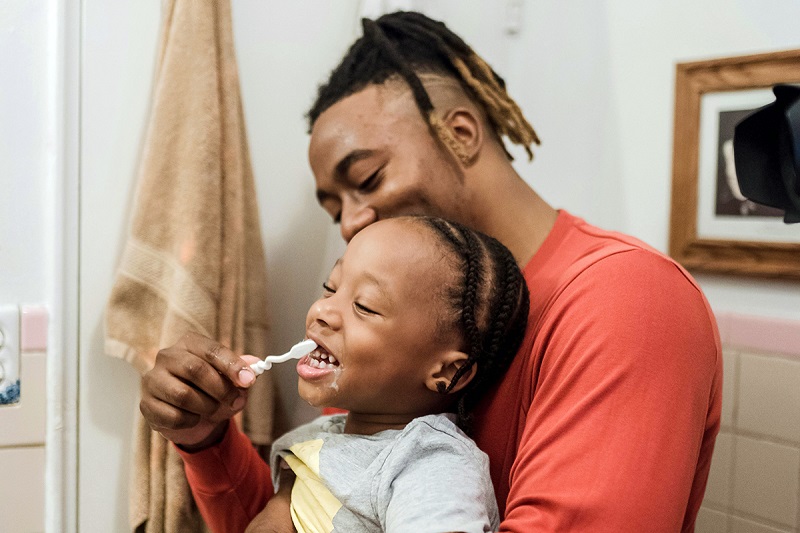 a parent doing teeth brushing to ta kid