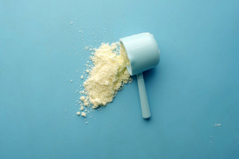 a spoon full of colostrum spilled on a blue surface