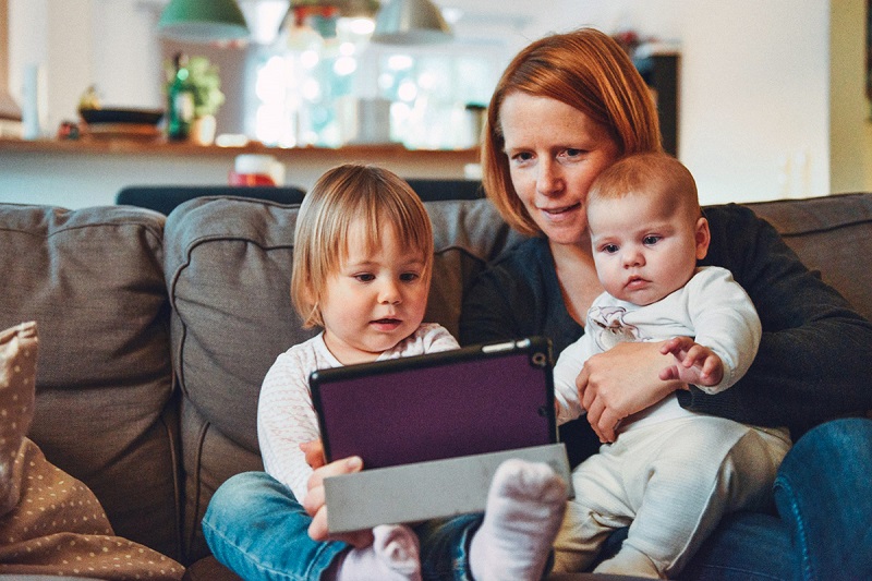 a parent with two children in the lap using tablet