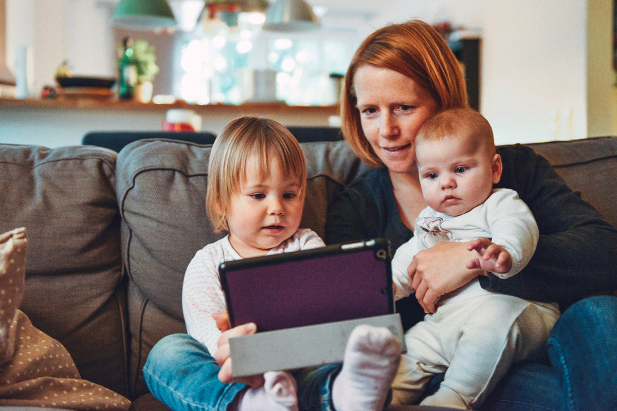 a parent with two children in the lap using tablet