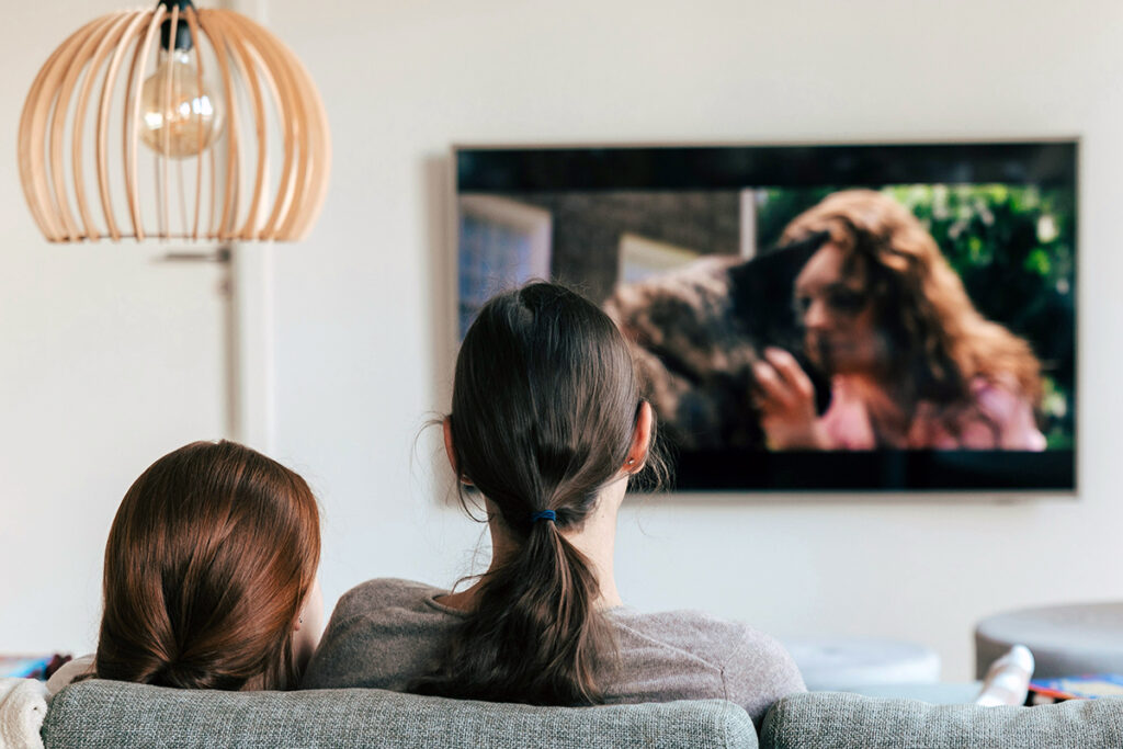 Two adults sitting on couch and watch TV