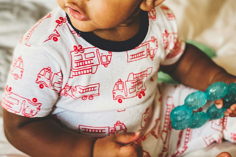 close up picture of a baby holding teether in hand