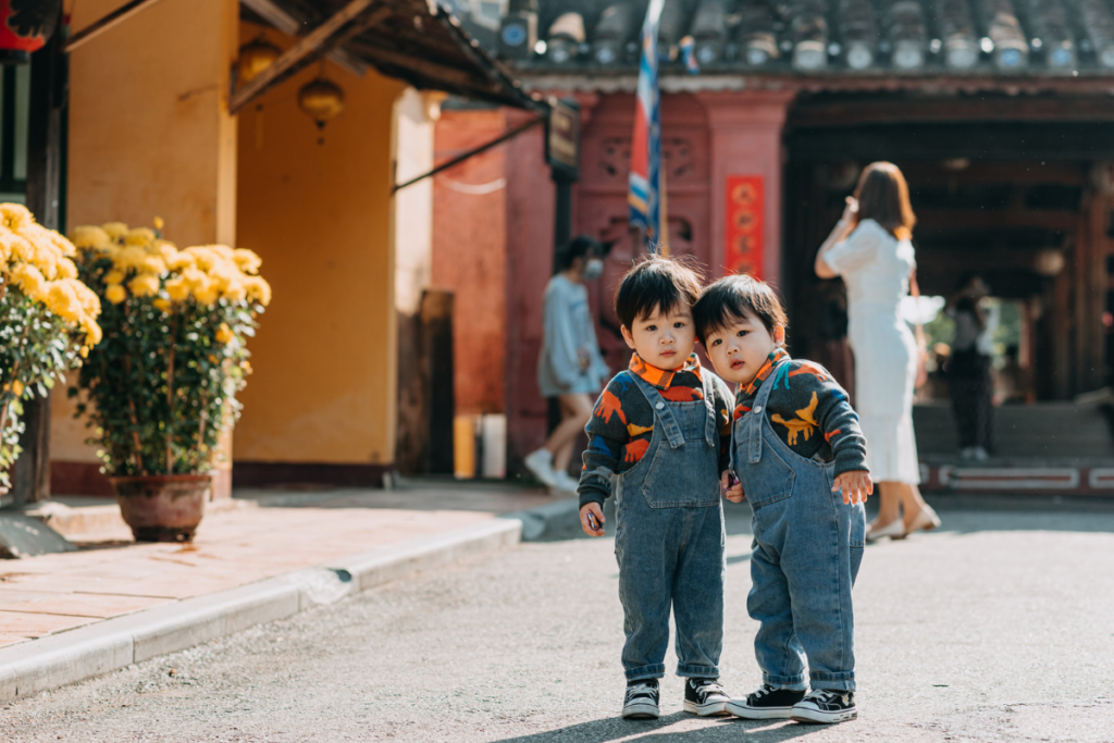 Twins standing outdoors.