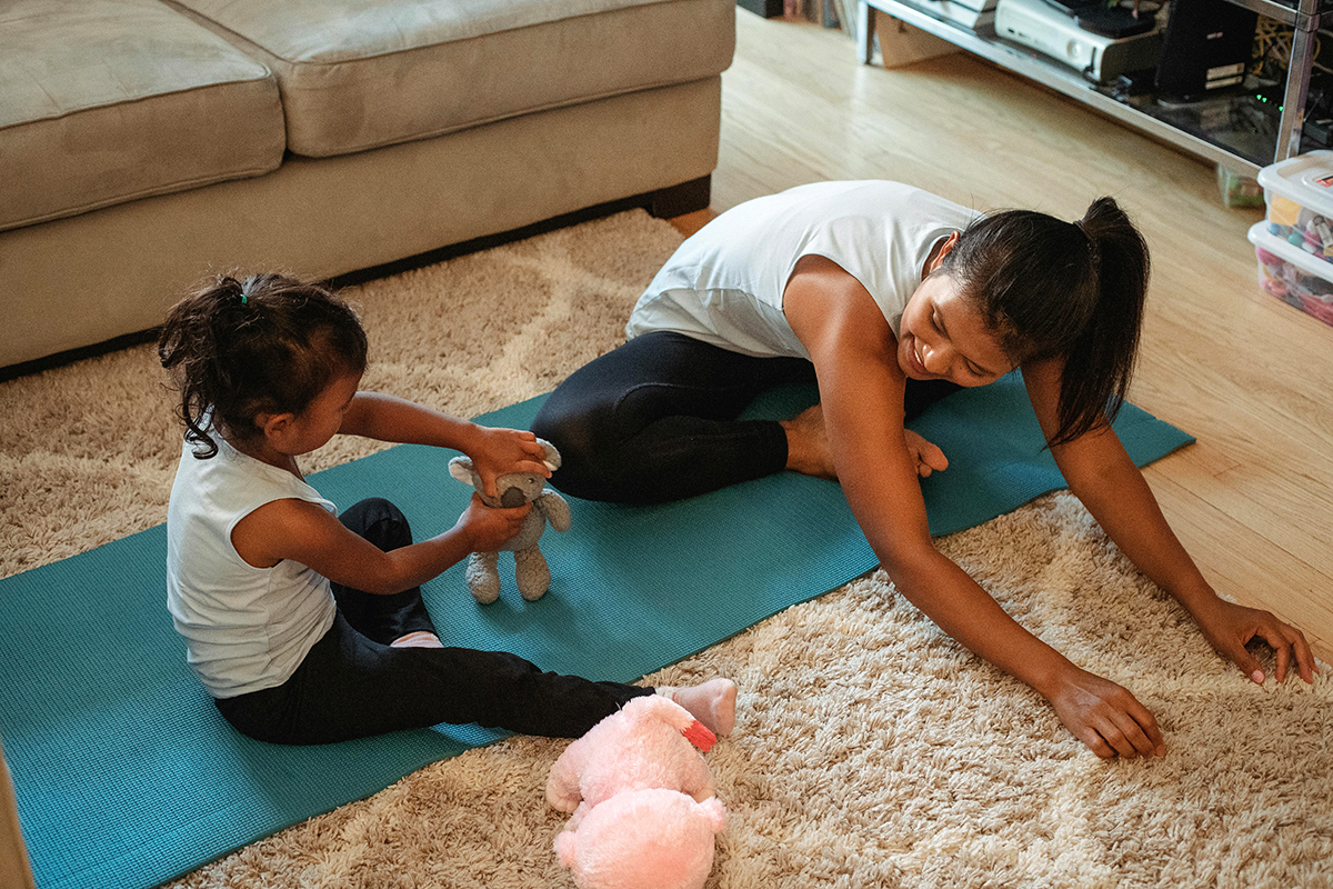 a parent and kid doing yoga on a yoga mat in a room