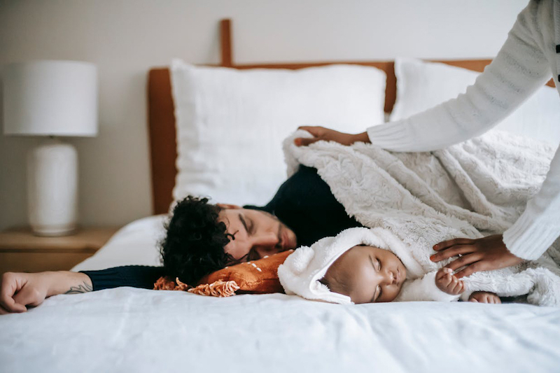 Parent and baby sleeping on bed