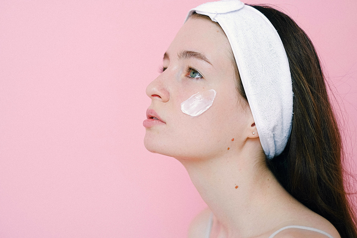 Person with headband on and cream on their face