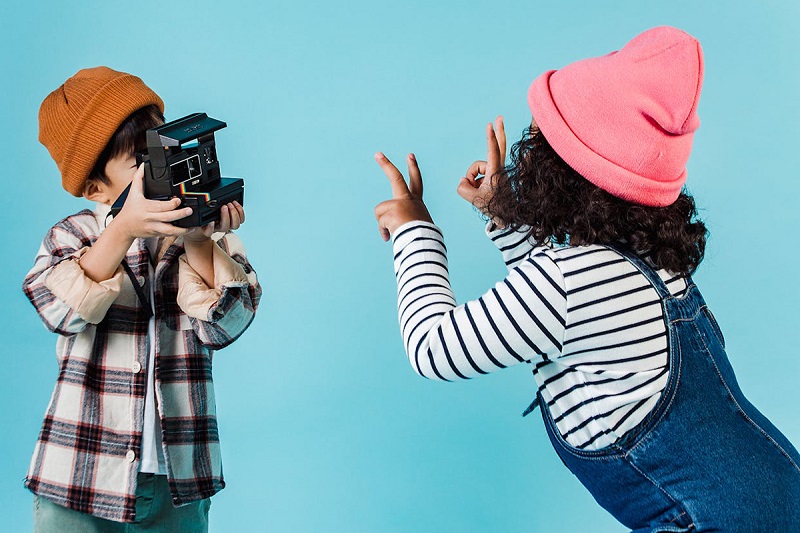 two kids posing and taking photograph of each other