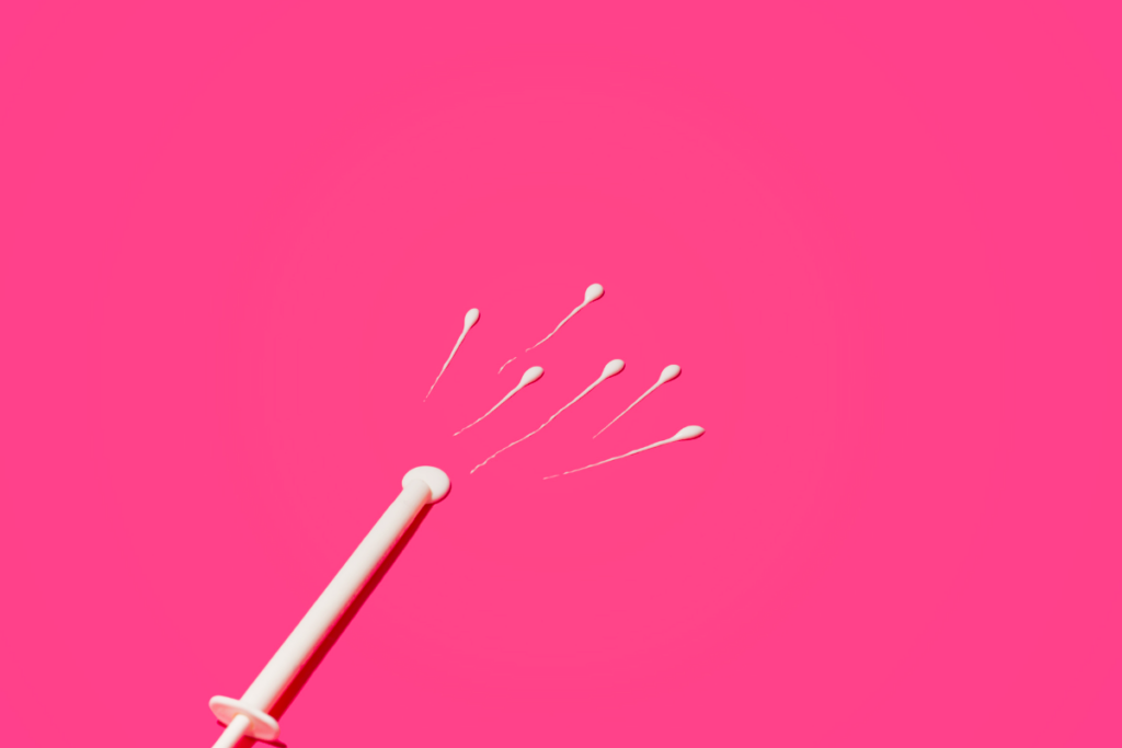 Sperms coming out of an IUI syringe in a pink background