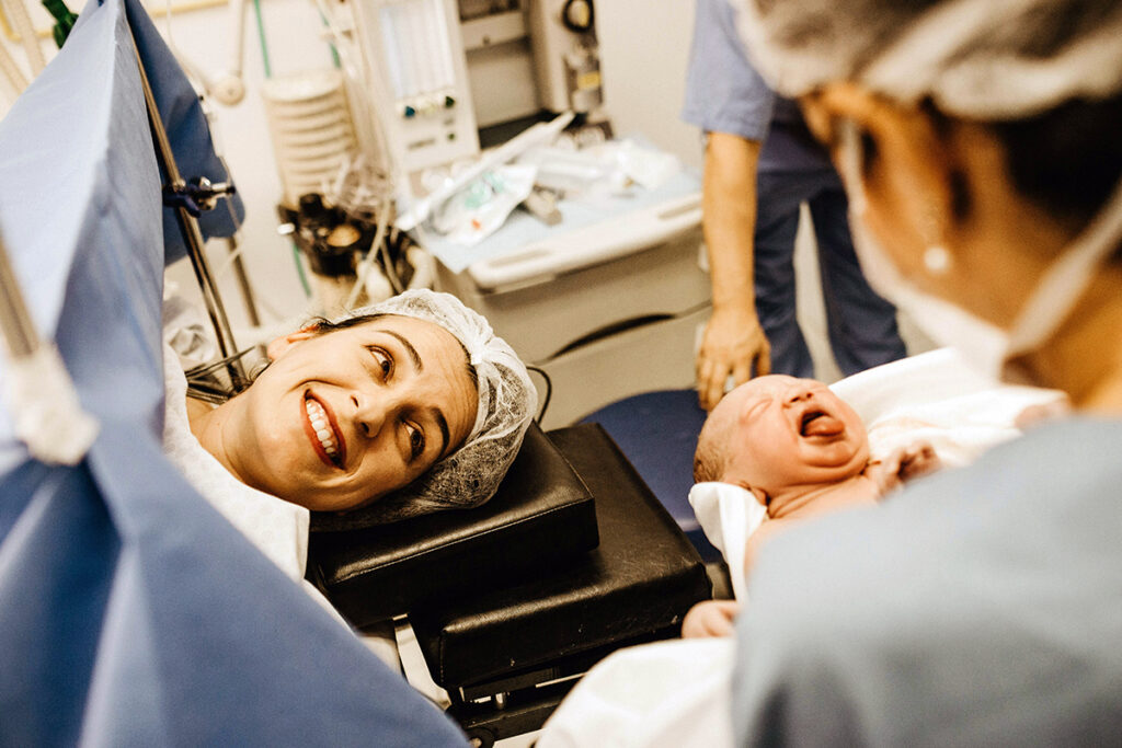 A person in delivery room looking at her baby