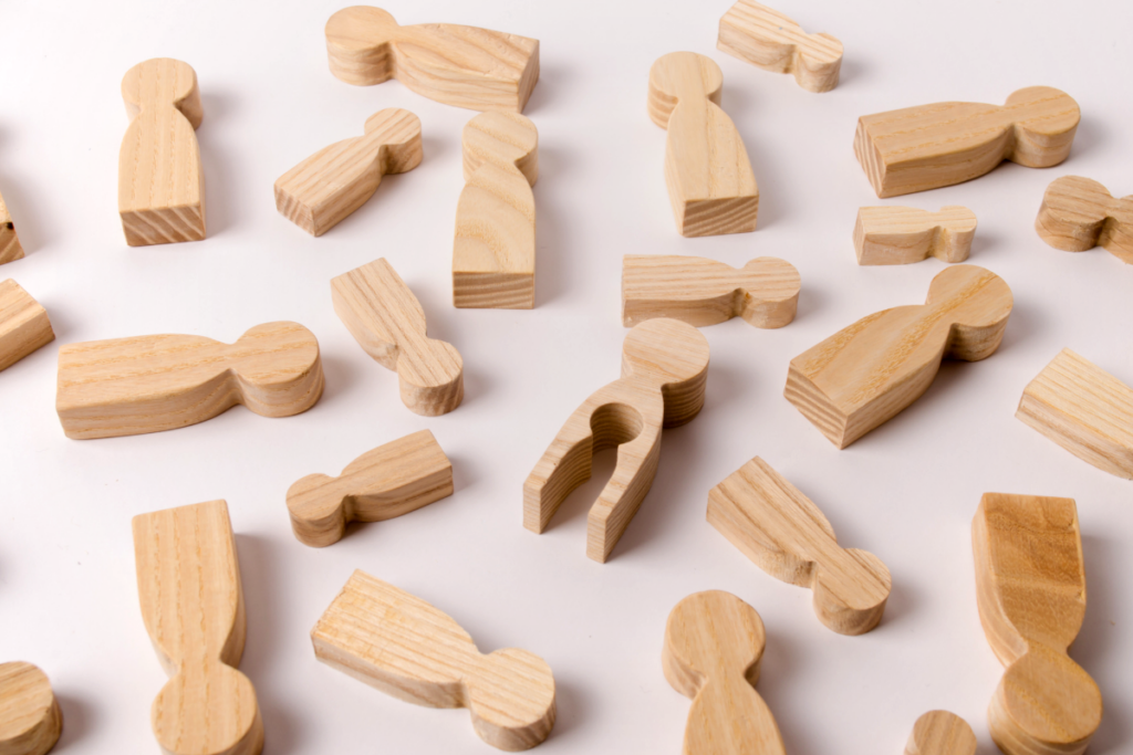 A bunch of people shaped wooden blocks where one block is missing a tiny person sub block