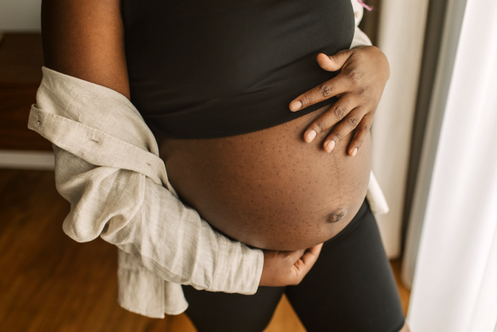 A pregnant person holding their belly